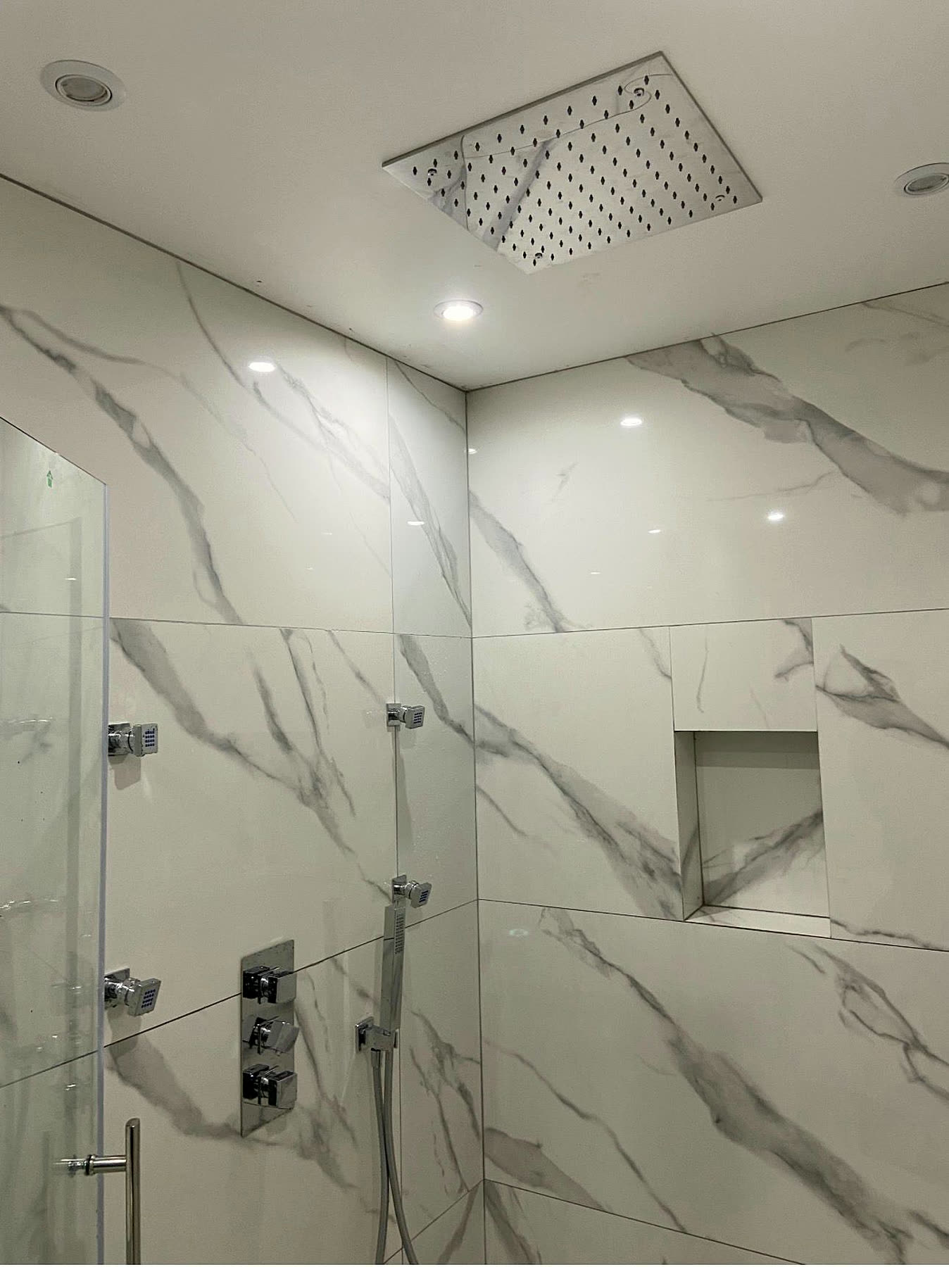 Douche à l'italienne réalisée par Sani-Chauffe : grès effet marbre, ciel de pluie encastré et jets latéraux