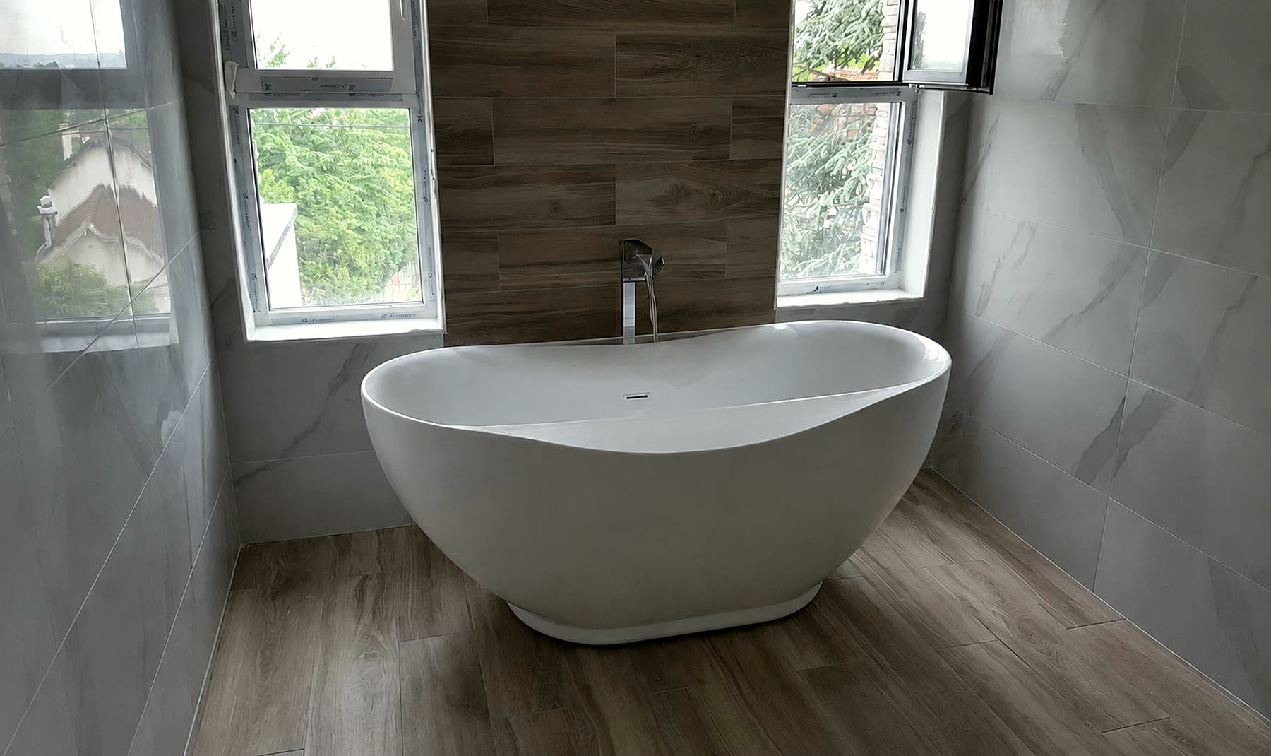 Baignoire îlot posée par Sani-Chauffe devant un mur en carrelage effet bois